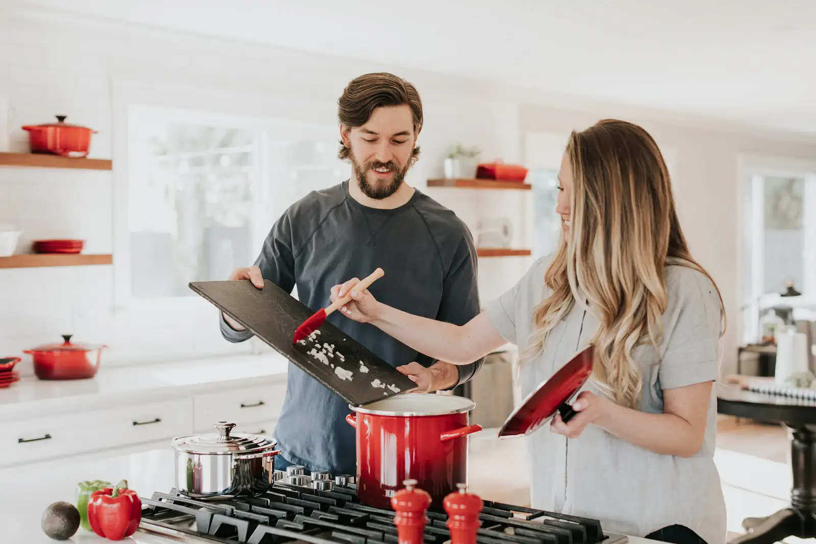 Two people cooking at a gas range in a white kitchen. Shown on the Countertops page for Rockford, IL.
